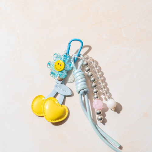 Bag charm keychain with a flower, hearts, and beads on a light background